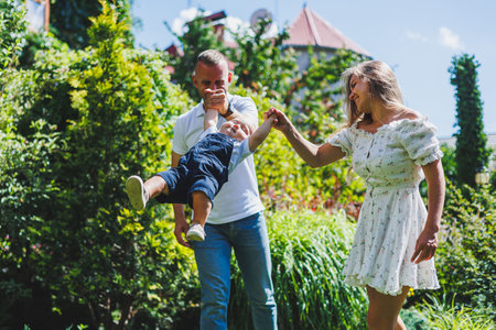 Two parents are playing on a walk with their toddler son. A young married couple, a man, a woman and...