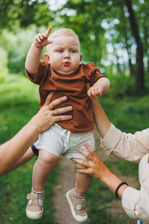 Baby boy close-up in the hands of mom and dad. Parents hold their son in their hands.の写真素材