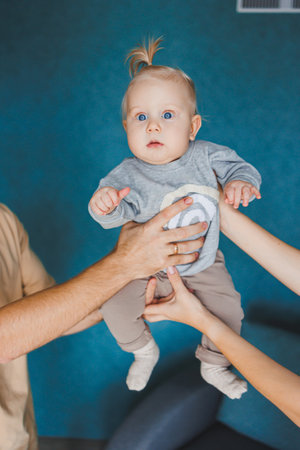 Baby boy close-up in the hands of mom and dad. Parents hold their son in their hands.の写真素材