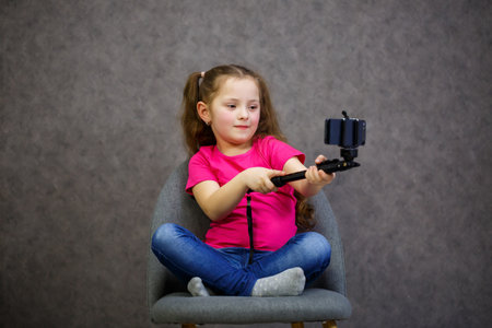 Girl in A T-shirt takes a selfie on her phone and posesの写真素材