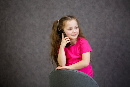 A young girl in a pink T-shirt talks on the phoneの写真素材