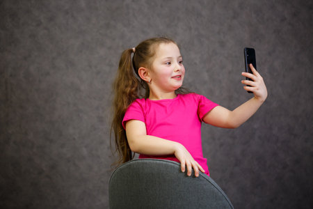 A young girl in a pink T-shirt talks on the phone