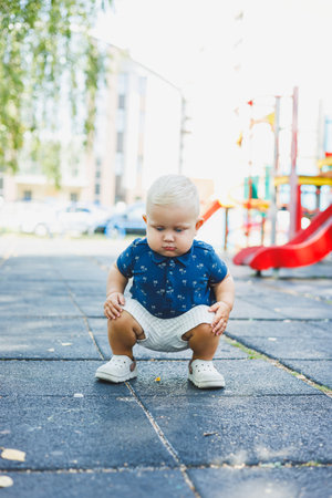 A little boy in shorts and a T-shirt is playing on the playground. A child runs and smiles while playing on the street.の写真素材