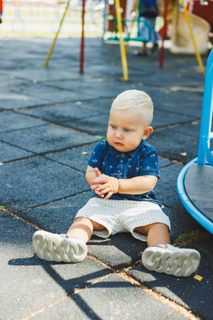 A little boy in a blue t-shirt and shorts is running on the playground. The child actively spends...