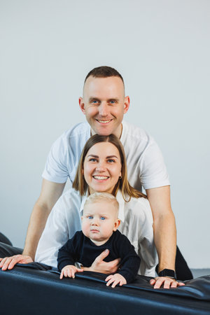 A happy family couple with a little son in their arms. Mom, dad and baby are hugging.の写真素材