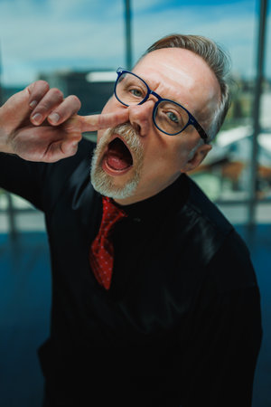 Bearded old man grimacing in glasses. The old grandfather's roof is falling and he grimaces.の写真素材
