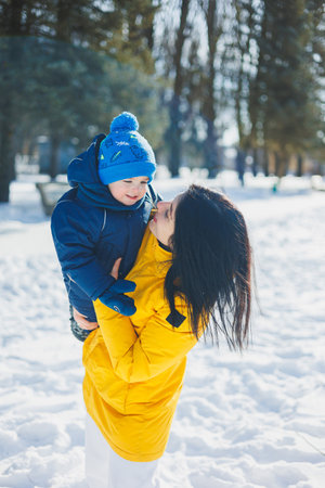 Happy mother playing snowballs with her little son. Winter walk of mother and son.の写真素材