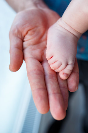 Baby's foot in dad's hand close-up. Baby's small foot.の写真素材