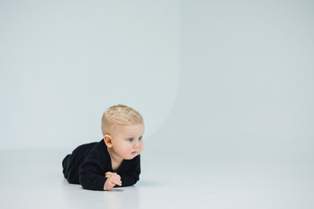 Blond baby crawling on the floor at home. Child development. Boy learning to crawl.