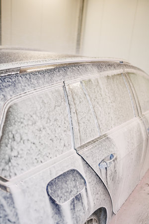 Dirty car heavily covered in thick foam. Blue car at self-service car washの写真素材