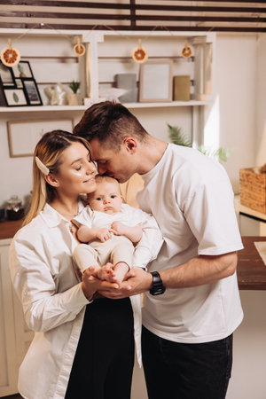 Happy family with newborn son in the kitchen. Family couple at home with son in the kitchen. Home family atmosphereの写真素材