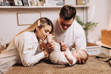 Smiling young family with child, father and mother with little baby, newborn child, having morning breakfast in home kitchen. Family enjoying parenthood at home.の写真素材
