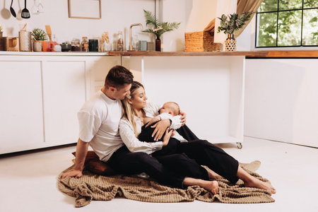 European family couple with baby resting at home. The couple hugs and holds their son in their arms.の写真素材
