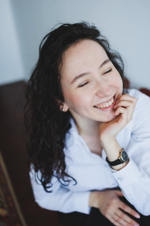 A cheerful young woman with beautiful curly hair beams with a bright smile, radiating genuine happiness and positivityの写真素材
