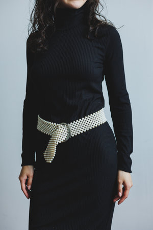 A stylish woman is elegantly wearing a black turtleneck dress that is beautifully accessorized with a distinctive beltの写真素材