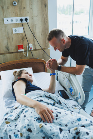 A heartfelt moment between a patient and their partner in a hospital room, reflecting love and care.の写真素材