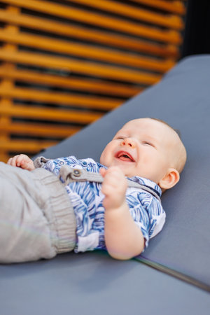A little boy in a summer shirt and shorts lies on a deck chair.の写真素材