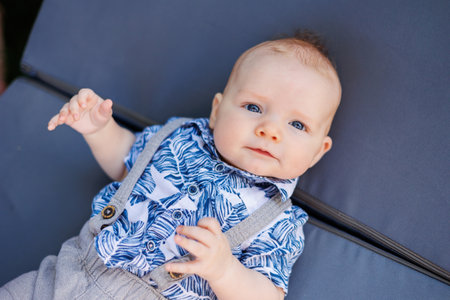A little boy in a summer shirt and shorts lies on a deck chair.