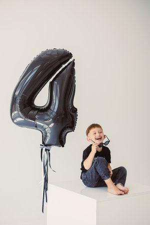 A delighted and cheerful child joyfully celebrating their 4th birthday with a stylish, vibrant black balloonの写真素材