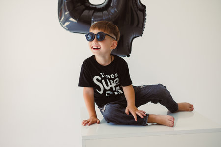 A cheerful and lively child poses with stylish sunglasses, showcasing a sense of playfulness and joy