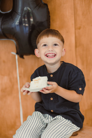 A joyful and happy child beams with excitement while holding up a slice of delicious cake, celebrating a special momentの写真素材