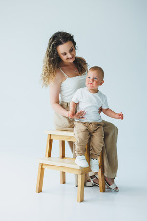 A heartwarming scene of a mother and her adorable toddler joyfully enjoying time together in a bright studioの写真素材