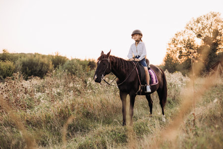 A young rider relishes a tranquil moment while riding horseback in a stunningly picturesque outdoor settingの写真素材