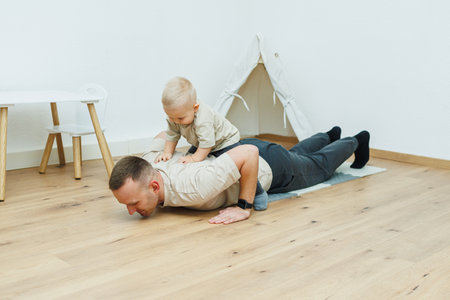 A father joyfully does pushups while his child playfully rides on his back enjoying the fun togetherの写真素材
