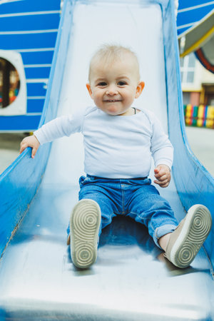 A happy baby joyfully slides down a colorful playground slide, showcasing pure joy and childhood innocenceの写真素材