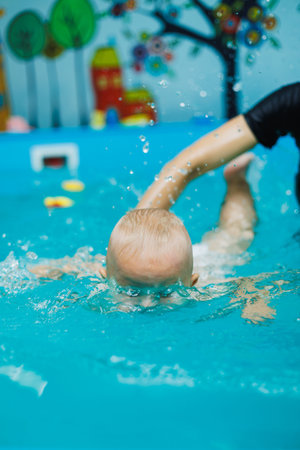 A coach teaches a baby boy to swim. Swimming pool for teaching children to swim.の写真素材