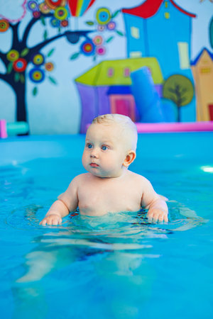 A baby learns to swim in a pool with a trainer. Children's pool. Swimming courses for children.の写真素材