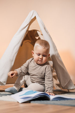 Adorable baby enjoying a book in a playful tent setting, perfect for family and child-themed...