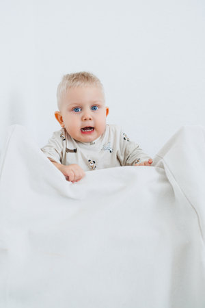 Smiling blond boy playing at home in bright living room. Toddler boy playing at home and smiling at camera.の写真素材