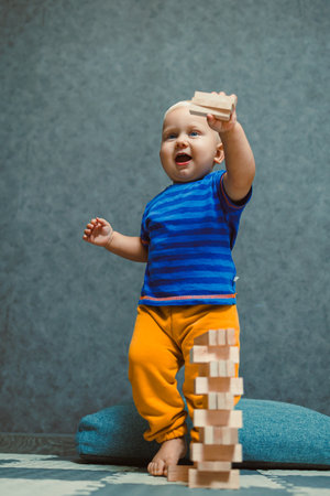 In a cheerful and playful indoor environment, a joyful toddler is happily stacking colorful wooden blocksの写真素材