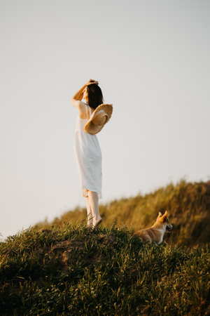A serene sunset scene featuring a woman in white with her loyal dog, creating an enchanting atmosphereの写真素材