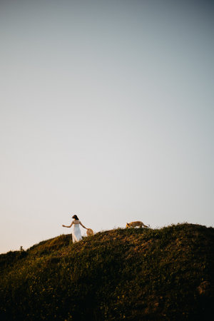 Woman in a field at sunset. Happy carefree woman in a black dress in a large field, at sunset. Walking under the setting sun in natureの写真素材