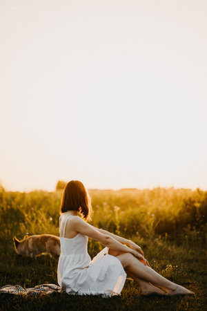 Woman in a field at sunset. Happy carefree woman in a black dress in a large field, at sunset. Walking under the setting sun in natureの写真素材