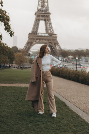 A fashionable and trendy woman poses gracefully and elegantly in front of the iconic Eiffel Tower in Parisの写真素材