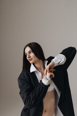 A fashionable young woman poses gracefully in an oversized blazer and white blouse, exuding confidence.の写真素材