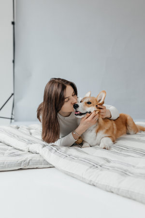 A truly joyful and heartwarming moment shared between a woman and her beloved corgi in a bright settingの写真素材