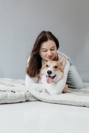 A woman joyfully enjoys a playful moment with her corgi, capturing the joys of pet companionship and loveの写真素材