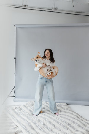 A joyful woman happily holds two adorable dogs in a vibrant studio setting, showcasing her love for petsの写真素材