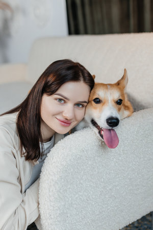 A young woman beams with joy beside a playful corgi, beautifully capturing the true essence of friendship and happinessの写真素材
