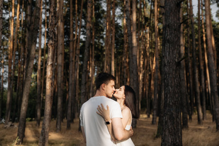 A loving couple shares an intimate moment among tall green trees, symbolizing their bond and connectionの写真素材
