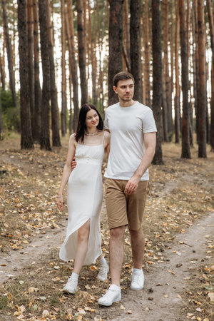 A couple strolls hand in hand through a tranquil forest path, showcasing their deep love and connectionの写真素材