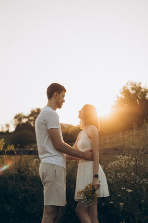 A couple sharing a beautiful and tender moment together in a sunlit field, surrounded by natures exquisite beautyの写真素材