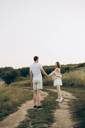 A young couple enjoys a lovely and romantic walk on a beautiful outdoor pathway surrounded by vibrant natureの写真素材