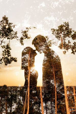 A stunning and beautiful silhouette of a couple intimately sharing a precious moment at sunset among lush treesの写真素材