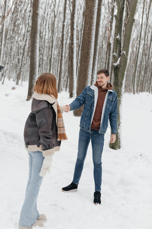 A loving couple walks in the snowy woods, embracing winter magic and creating lasting memories togetherの写真素材