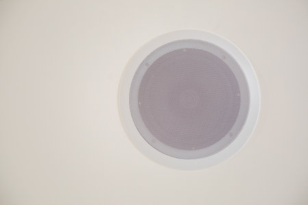 There is a white circular air vent that is installed on a plain white wall, which serves its purpose efficientlyの写真素材